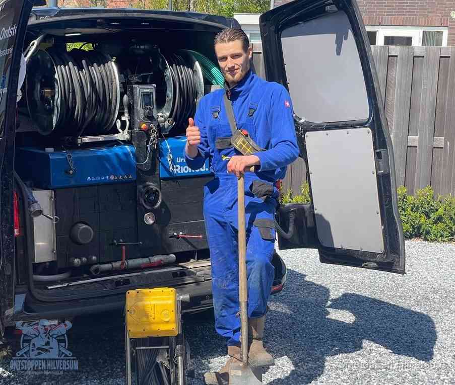 Een monteur bij de werkbus met grote hogedruk-slanghaspels, apparatuur voor hardnekkige afvoerverstoppingen in Hilversum