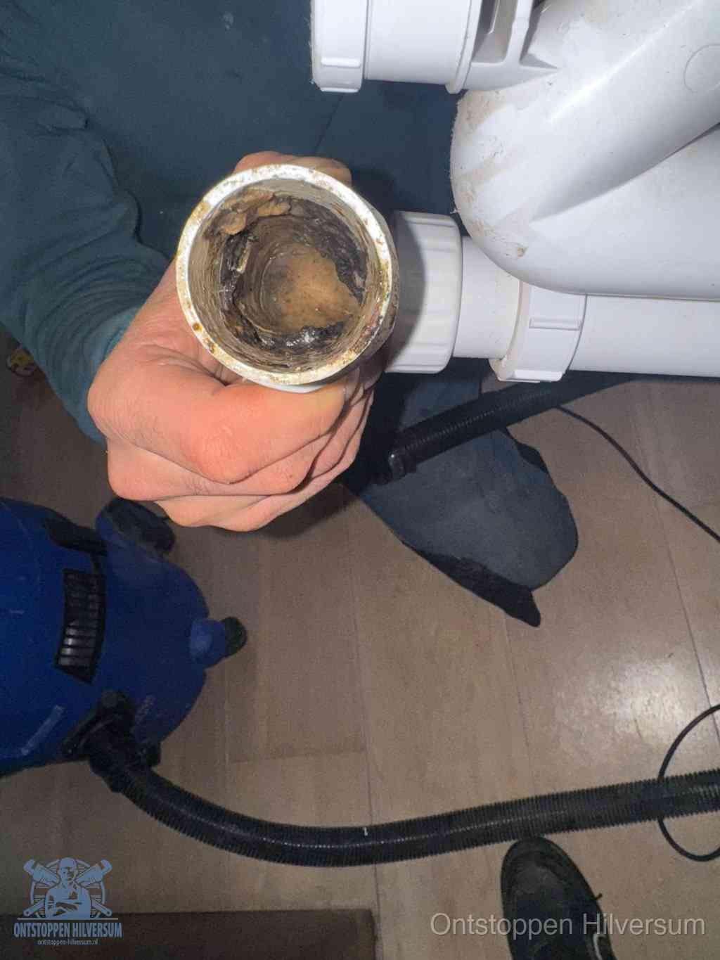 Een losgekoppelde afvoerbuis die van binnen volledig is dichtgeslibd met vet en aanslag, de meest voorkomende oorzaak van een verstopte gootsteen in Hilversum
