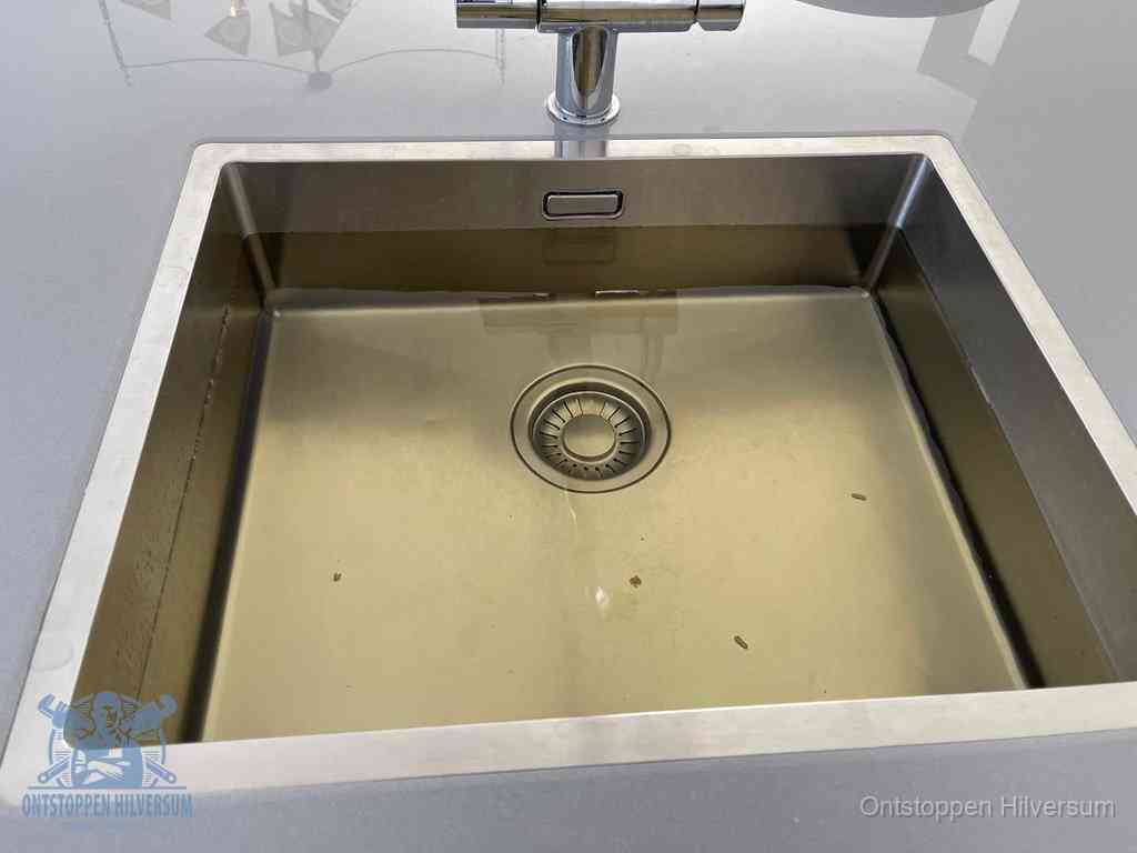 Stilstaand water in een rvs spoelbak dat niet wegloopt, een duidelijk signaal van een gootsteenverstopping in Hilversum