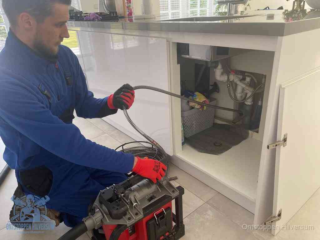 Een monteur reinigt de keukenafvoer grondig met een veermachine om terugkerende gootsteenverstoppingen te voorkomen in Hilversum