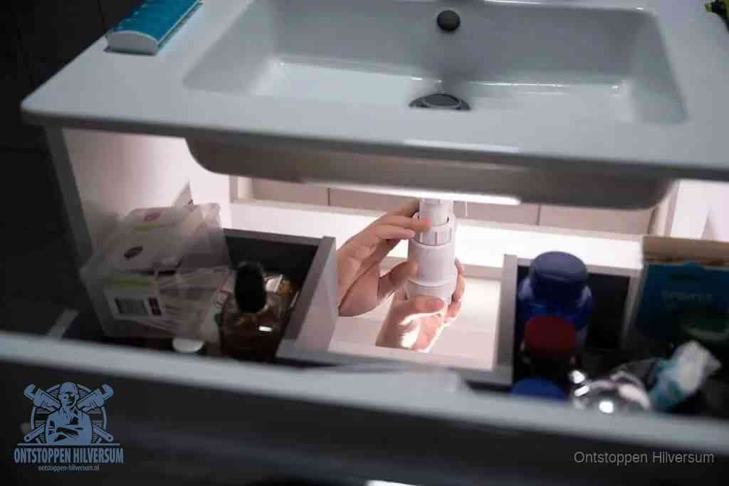 Een pompfles met zeep boven een wastafel in de toiletruimte, de warm water en afwasmiddel-methode om de wc te ontstoppen in Hilversum