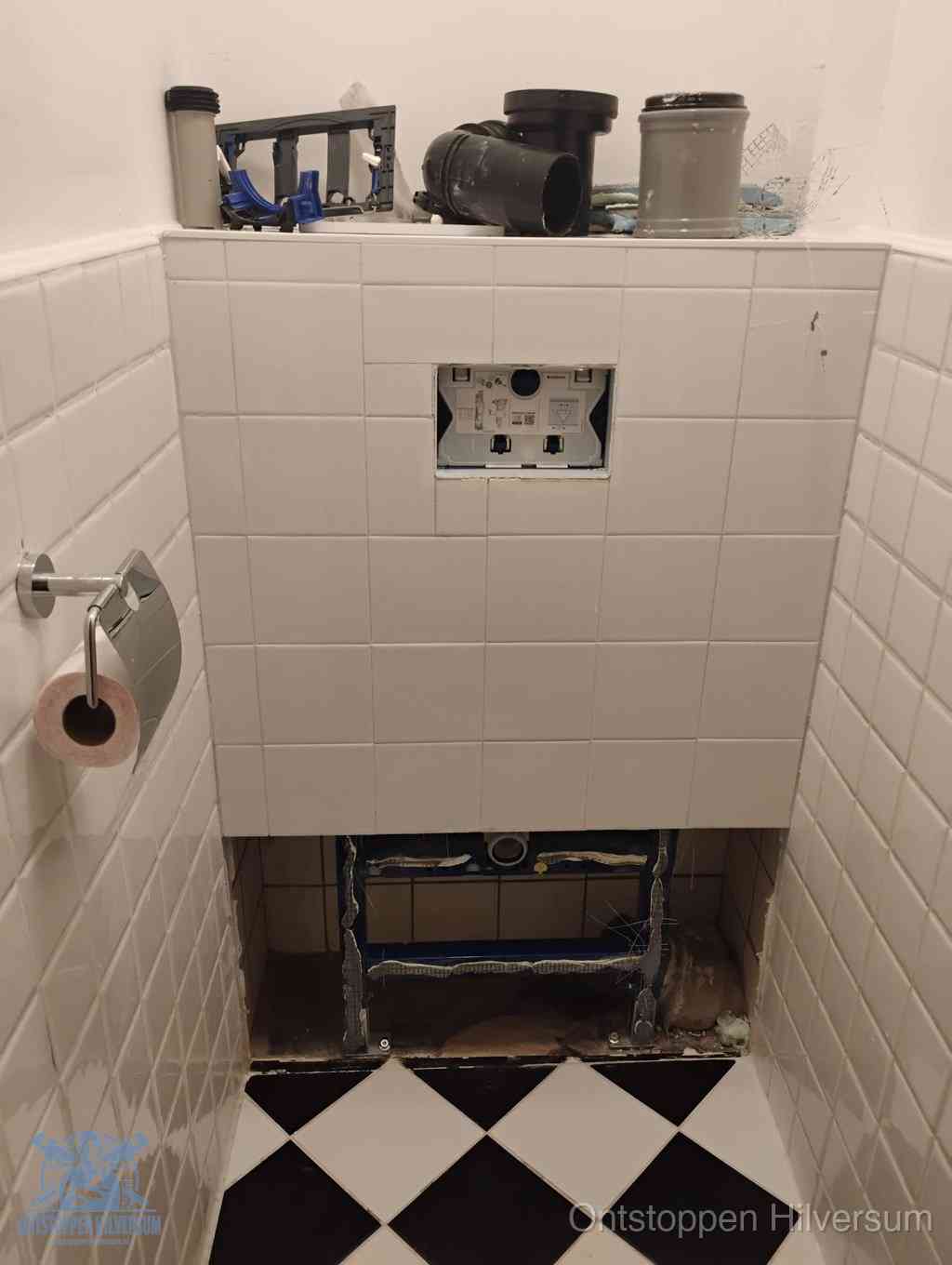 Een toiletruimte waar het hangtoilet en de inbouwreservoir-onderdelen zijn vrijgelegd voor onderhoud, periodiek nazicht voorkomt een wc-verstopping in Hilversum