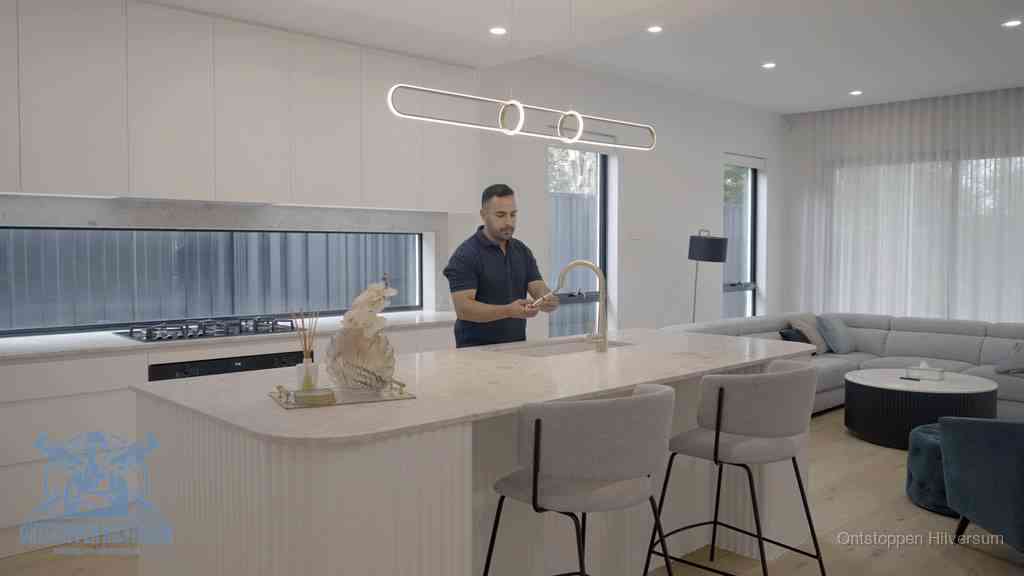 Een bewoner bij de keukenspoelbak die zelf aan de slag gaat met een verstopte gootsteen in Hilversum